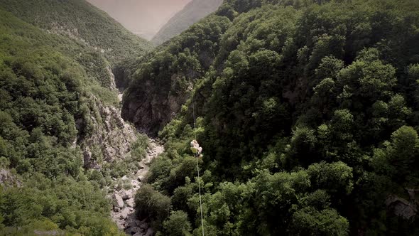 Aerial view of couple canopying over the forest in zip-line at Slovenia.