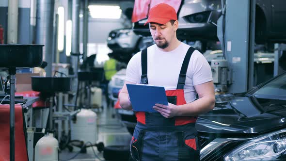 Auto Mechanic Writing Down Notes on His Tablet