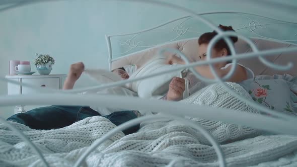 Young Beautiful Couple Having Fun in Bed, They Fight By Cushions, Laughing, Slow Motion