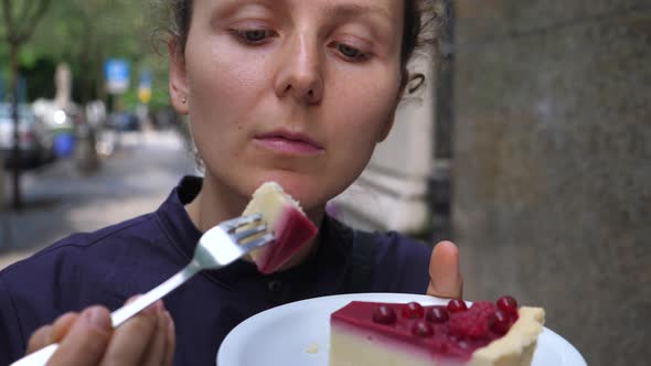 Close Up of Young Woman Tasting a Piece of Raw Vegan Raspberry Cake Outdoors. Healthy Fun Vegan