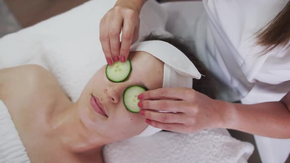 Caucasian woman lying back while beautician gives her a facial