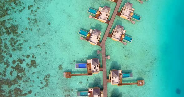 Aerial drone view of scenic tropical island and resort hotel with overwater bungalows in Maldives