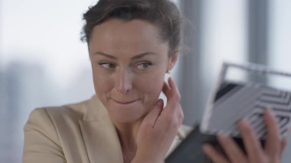 Closeup Portrait of Charming Confident Caucasian Businesswoman Adjusting Makeup Indoors Looking at