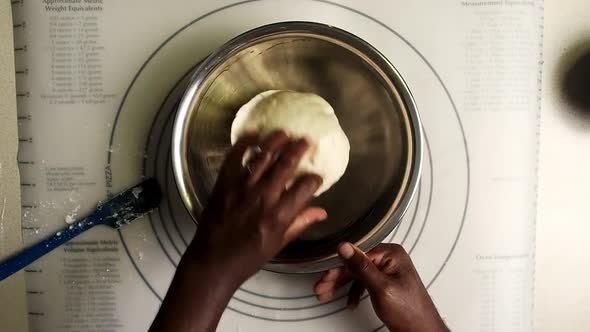 Overhead view of hands put dough in a oil bowl and covered the bowl