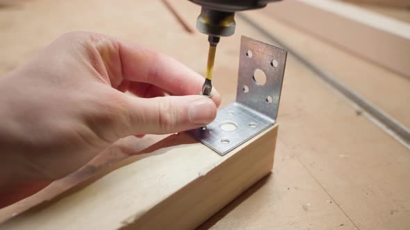 Screwing a Metal Corner Into a Wooden Block Using a Black Selftapping Screw and an Electric