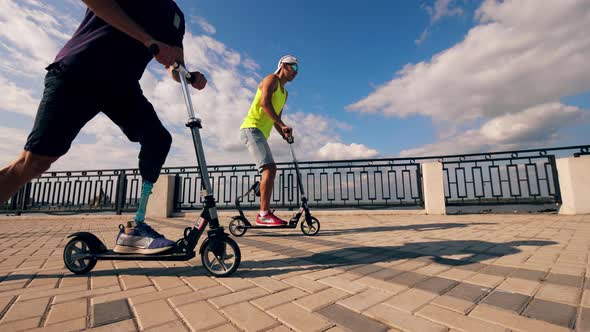 Men with Prosthetic Legs Are Riding Scooters Together