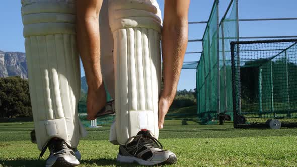 Cricket player tying his batting pads during a practice session