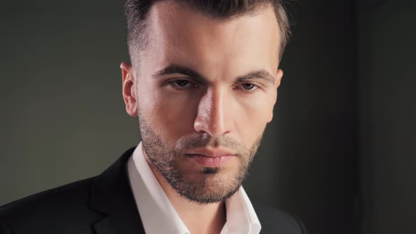 Portrait of Young Elegant Business Man Posing at Dark Office Near Window