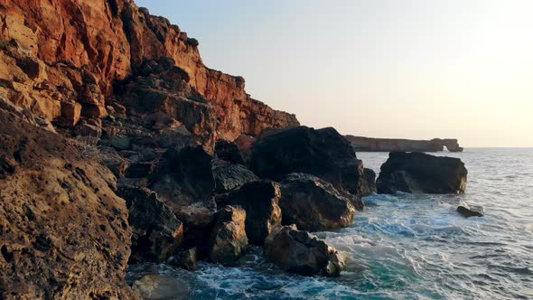 Aerial View. Sea Waves Splashing on Cliifs on a Sunset Background