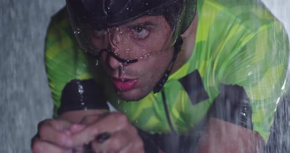 Triathlon Athlete Riding a Professional Racing Bicycle on an Intense Workout in Dark with Rain