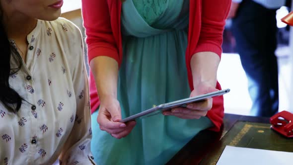 Two female business executive interacting over digital tablet