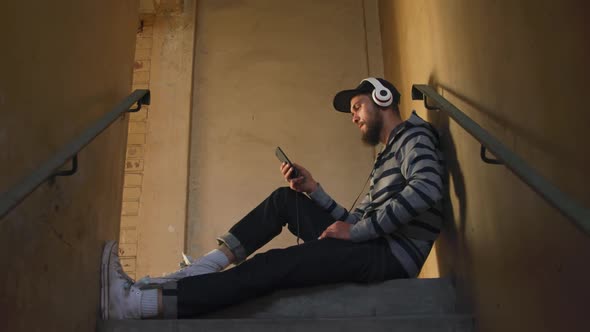 Young man listening to music in empty warehouse