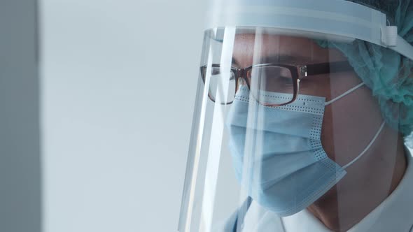 Studio portrait of young professional medical doctor in mask, hat and protective visor.