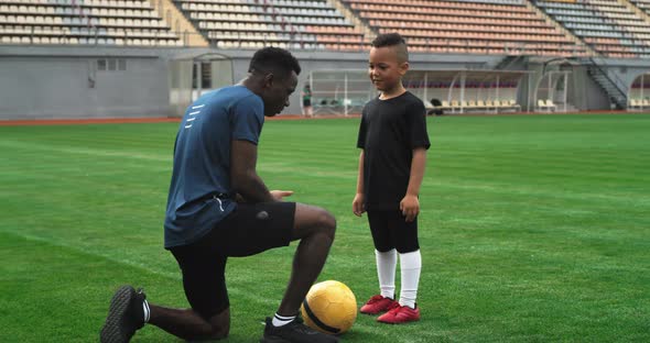 Black Father Teaching Son to Handle Football Ball