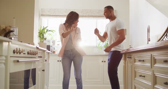 Happy biracial couple dancing together and having fun in kitchen