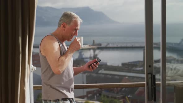 Senior man using his mobile phone and drinking coffee