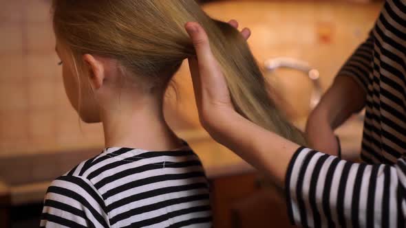 Careful Mother Brush Comb Daughter Child Long Hair with Colorful Comb Brush Wearing Striped Dress at