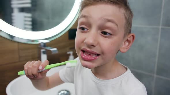 10-Aged Boy Cleaning His Teeth Using Toothbrush and Toothpaste, Standing Near the Bathroom Mirror