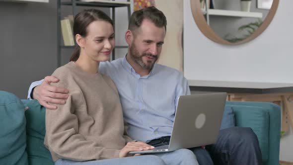 Couple Making Online Video Call on Laptop Sitting on Sofa