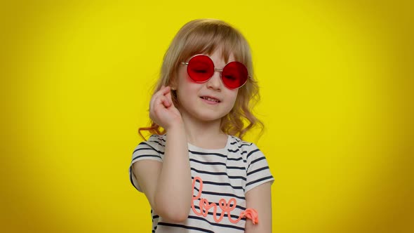 Happy Playful Kid Girl in Sunglasses Blinking Eye Looking at Camera with Smile Winking Flirting