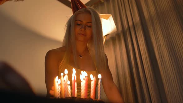 Atrtactive Smiling Woman Looking at Man Lighting Candles on Birthday Cake