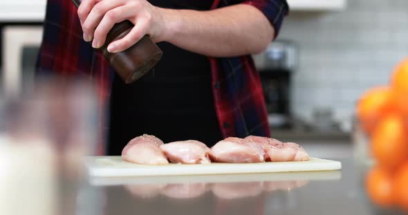 Man sprinkling black pepper on meat at home 4k