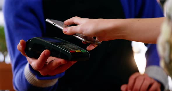 Woman paying bill through smartphone using NFC technology