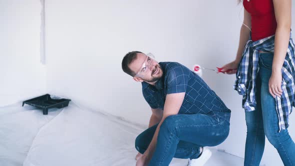 Man Covers Floor with Foil Near Girl with Roller in Room