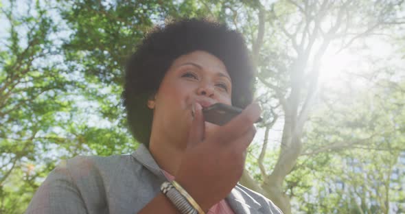 Happy plus size biracial woman talking on smartphone in park