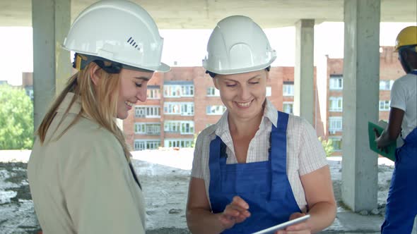 Construction Worker and Engineer Working on Building Site, Using Digital Tablet