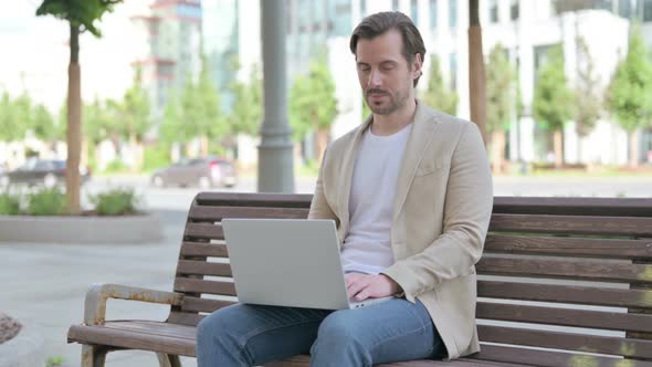 Thumbs Up By Young Man with Laptop Sitting on Bench