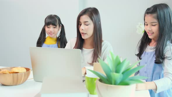 Asian single mother teaching homework to her little sibling daughter child