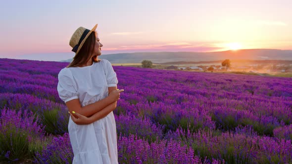 Beautiful Young Woman Wearing White Dress and Hat Standing in a Lavender Field