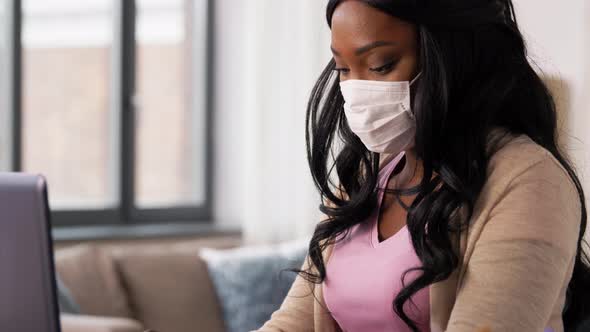 Woman in Mask with Laptop Working at Home Office