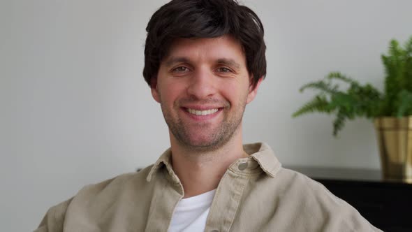 An Attractive Confident Man Looking Into the Camera Sitting in a Modern Living Room