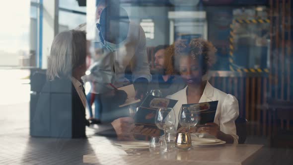 View Through Window of Diverse Couple Ordering Meal in Restaurant
