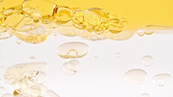 Slow Motion of Moving Yellow Golden Oil Air Bubbles in Water Rising Up on Light White Background