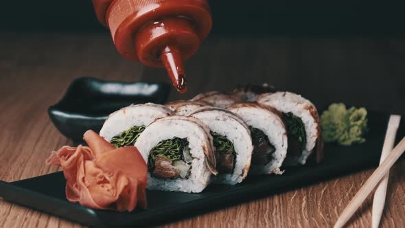 Appetizing Sushi is Poured with Sweet Sauce on a Wooden Table in Restaurant