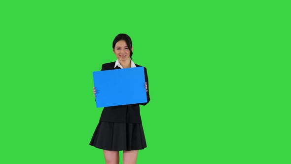 Cute Girl Holding Empty Board Announcing or Presenting Something on a Green Screen, Chroma Key.