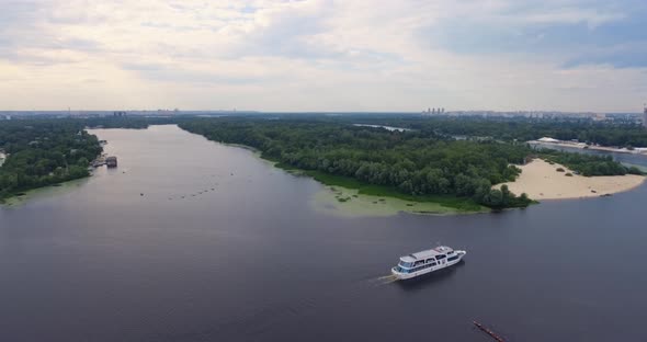 Passenger Ship Sails along City River Moving Away