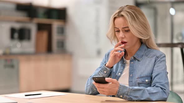 Unhappy Young Woman with Loss on Smartphone at Work