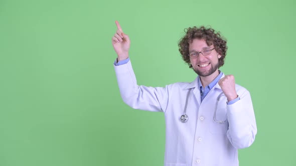 Happy Young Bearded Man Doctor Pointing Up and Getting Good News