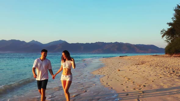 Two people happy together on luxury tourist beach break by blue lagoon with white sandy background o