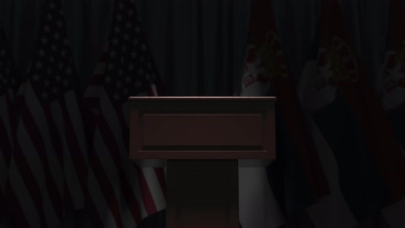 Many Flags of Serbia and the USA Behind Speaker Tribune alt