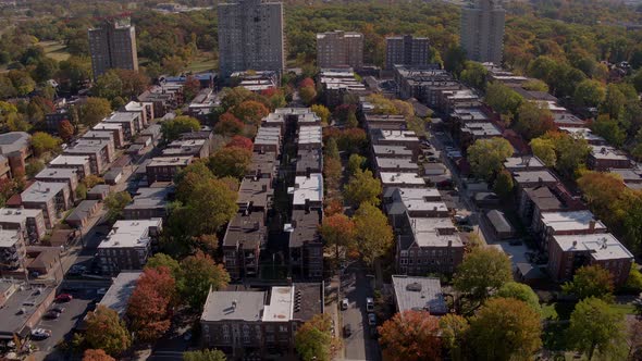 Flyover a park in the fall tilts up to reveal a residential city neighborhood and a skyline on the h