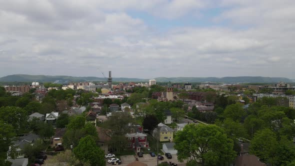 Drone view over midwest city with diverse building structures, tree lined streets, and bluffs.