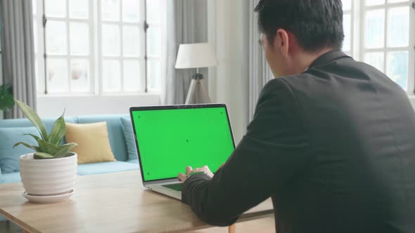 Asian Businessman Wearing Business Suit Typing On Green Screen Computer While Working At Home