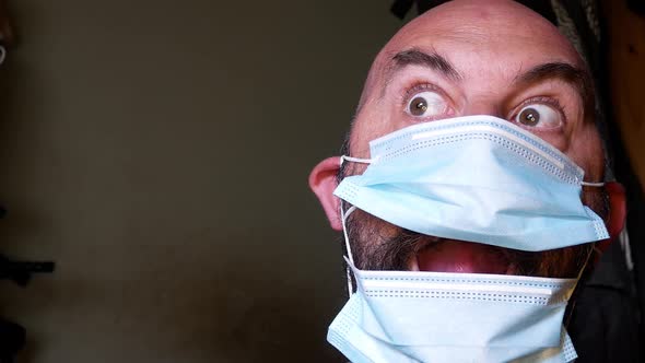 Closeup comedy male surprise posing in medical PPE corona virus mask looking at camera room for copy