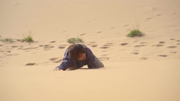 A Man in an Office Cloth Crawls Up a Dune in a Desert