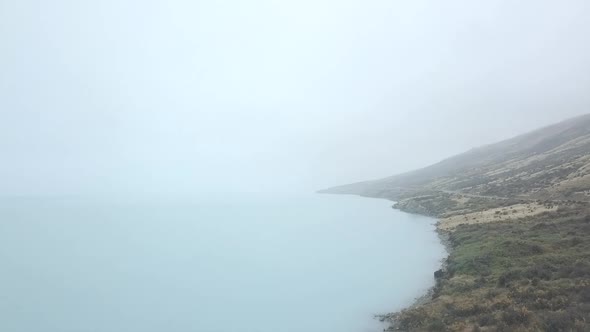 Scenic mountain silhouettes across lake with hazy horizon